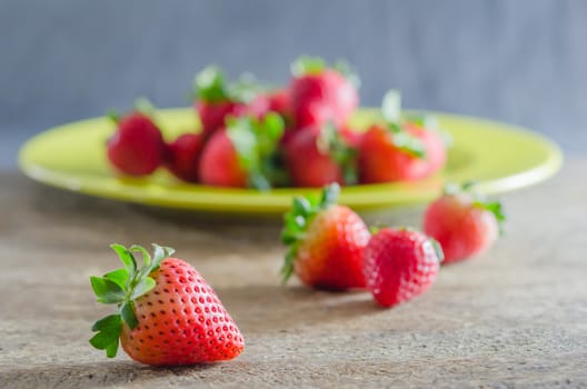 still life of fresh red strawberries on dish over wooden background