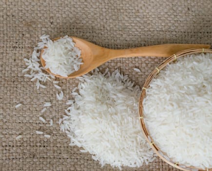 white rice grains with wooden spoon  on sackcloth