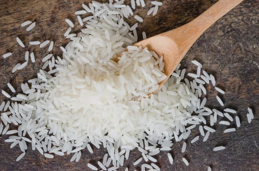 white rice  grains with wooden spoon on wooden table