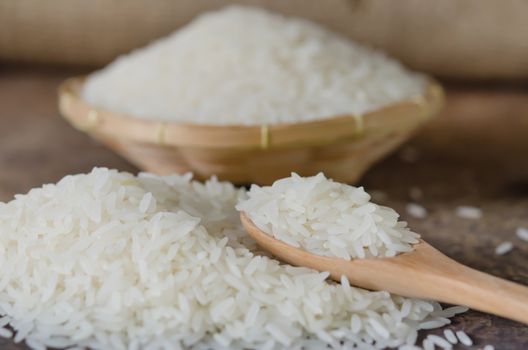 white rice  grains with wooden spoon on wooden table
