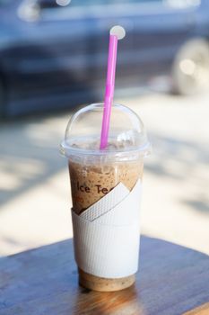 Coffee ice. Plastic glass is placed on a wooden table.