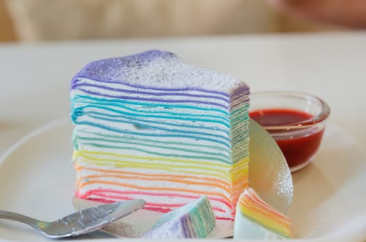 Rainbow crepe cake served with strawberry sauce
