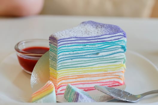 Rainbow crepe cake served with strawberry sauce