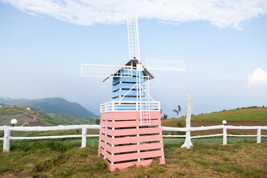 Wind turbine made of wood. Located on the lawn Behind the clear sky