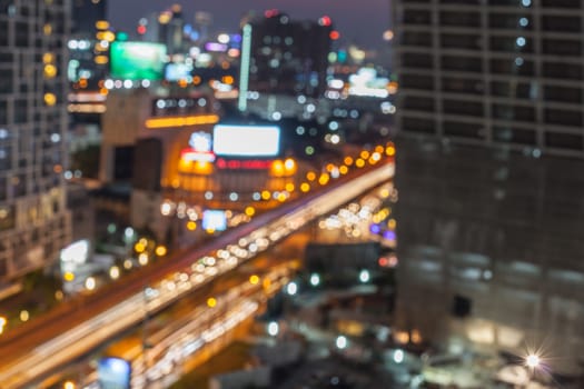 Abstract background of the night light trails with the modern building and traffic on highway, shallow depth of focus