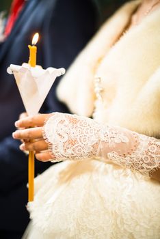 Wedding ceremony in orthodox church. Bride and groom holding the candles. Close up.