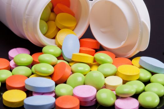 lot of colorful pills with white box on black background