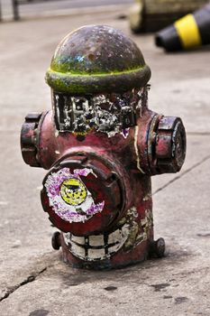 Old and dirty red hydrant on the sidewalk