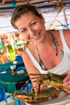 girl holding a raw lobster and smiling