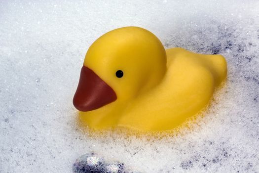 A rubber duck floating in bubbles in a bathtub.