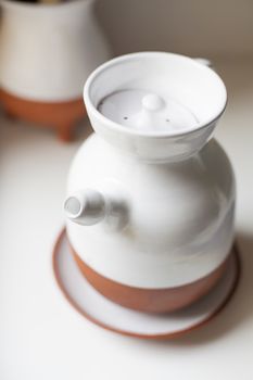 ceramic white and orange jug with spout and top cover on a plate for olive oil to cook in the kitchen