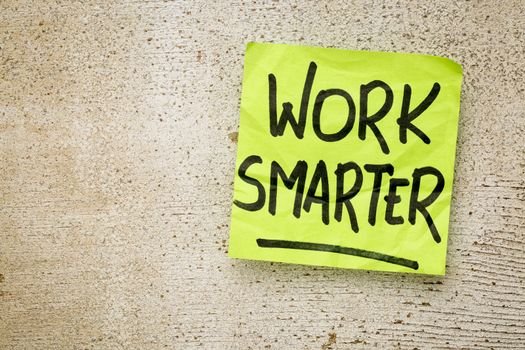 work smarter reminder on a green sticky note against rustic barn wood p productivity concept