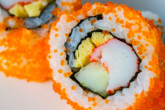 extreme close-up California Maki Sushi with Masago - Roll made of Crab Meat, egg, Cucumber inside. Masago (smelt roe) outside, soft focus, middle focused