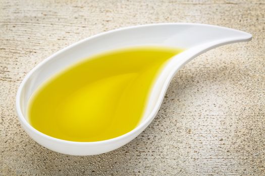 olive oil in a teardrop shaped bowl against white painted grunge wood