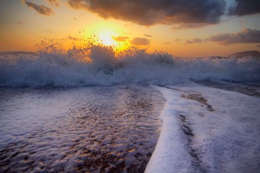 Gentle warm sea on backdrop of enchanting sunset. Foamy surf. Mediterranean sea.