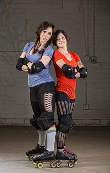 Pair of confident female roller skaters derby standing