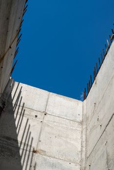 Grey concrete walls with reinforcing bars against the blue sky background