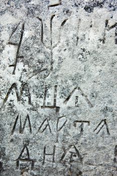 The surface of the old cross gravestone with engraved Old Church Slavonic inscriptions. Kyiv, Ukraine. Close up.