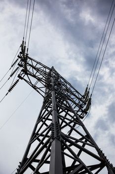 Electricity pylon against the cloudy sky background.