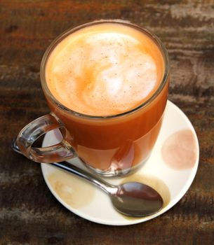 Cup of hot Thai tea on the wooden desk