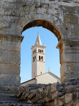 Bell tower of Saint Anthony Church in Pula, Croatia seen through the arc of Pula Amphitheater
