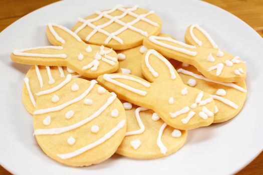 Close up of a pile of iced Easter themed biscuits on a plate - rabbit and egg designs