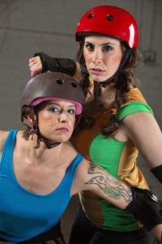 Two beautiful tough roller derby skaters with helmets
