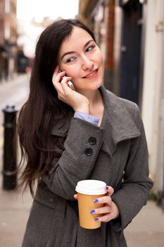 young woman on the phone with a take away coffee