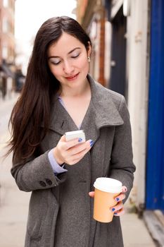 young woman checking her text messages with a coffee