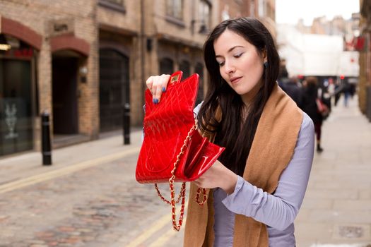 young woman looking for something in her handbag
