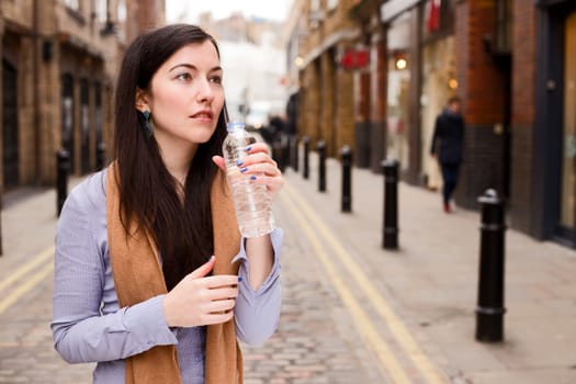 young woman drinking water in the street.