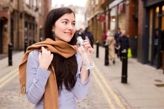 young woman drinking water in the street