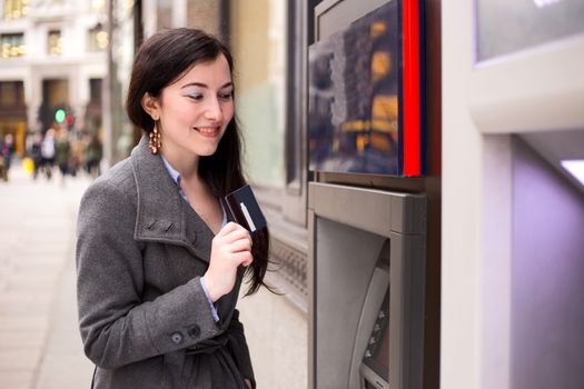 young woman showing her card at the cash machine.