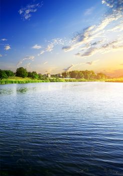 Big calm river near village at sunrise