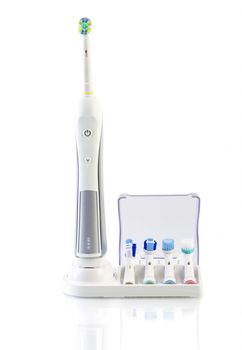 Electric toothbrush with stand charger and four spare brushes on white background
