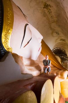 White tourist metitating by Huge Reclining Buddha Image at Manuha Pagoda, Bagan, Myanmar.
