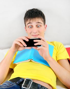 Surprised Student with a Book and Cellphone on the Bed