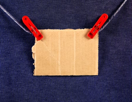 Cardboard on the Rope on the Blue Textile Background