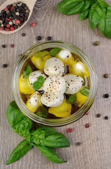 Baby mozzarella in olive oil with herbs in a glass jar