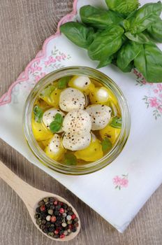 Baby mozzarella in olive oil with herbs in a glass jar