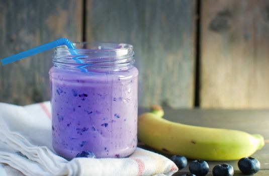 Blueberry flavored diet smoothie in a jar with a straw