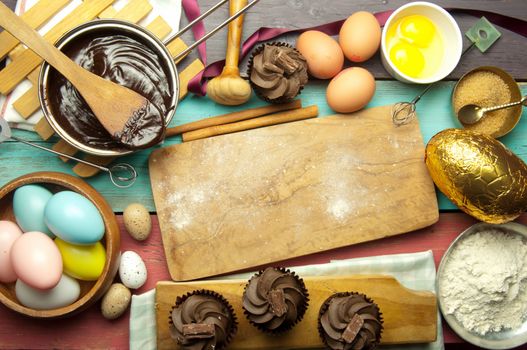Easter kitchen with baking ingredients including hot chocolate, eggs and flour and empty chopping board 