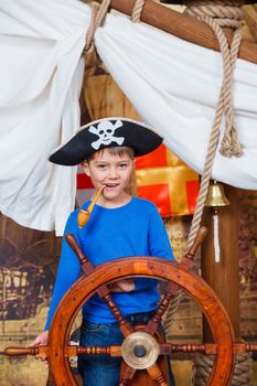 Cute little boy wearing pirate costume on the deck of a ship