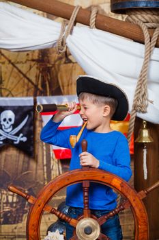 Cute little boy wearing pirate costume on the deck of a ship