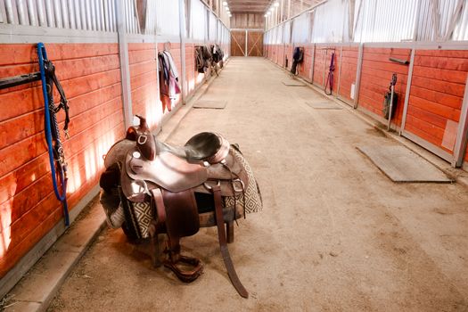 A saddle waits to be mounted on horses back at stables