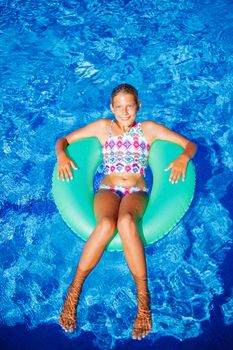 Funny girl swims in a pool in an green life preserver