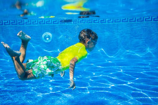 Underwater happy little boy in swimming pool
