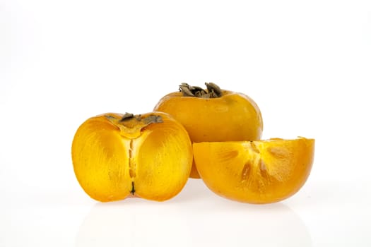 Persimmons, one whole and one cut in two pieces isolated on a white background