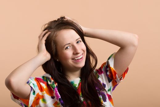 Fashion portrait of beautiful brunette young woman with perfect skin, hand in hair and smile expression