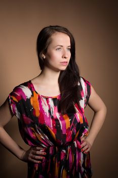 Fashion portrait of beautiful brunette young woman with perfect skin and long hair on beige background